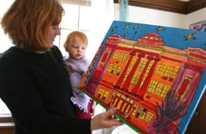 Artist Jenny Heyden showing her daughter Helen a painting she donated to SEED over a decade ago.